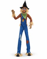 Towering scarecrow animatronic with blue illuminated eyes, pointed black hat, green neckerchief, plaid shirt and patched blue dungarees