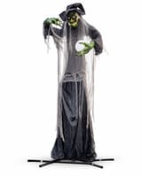Giant green-faced witch animatronic with black hat, grey hair, tattered black dress and crystal ball on a metal floor stand