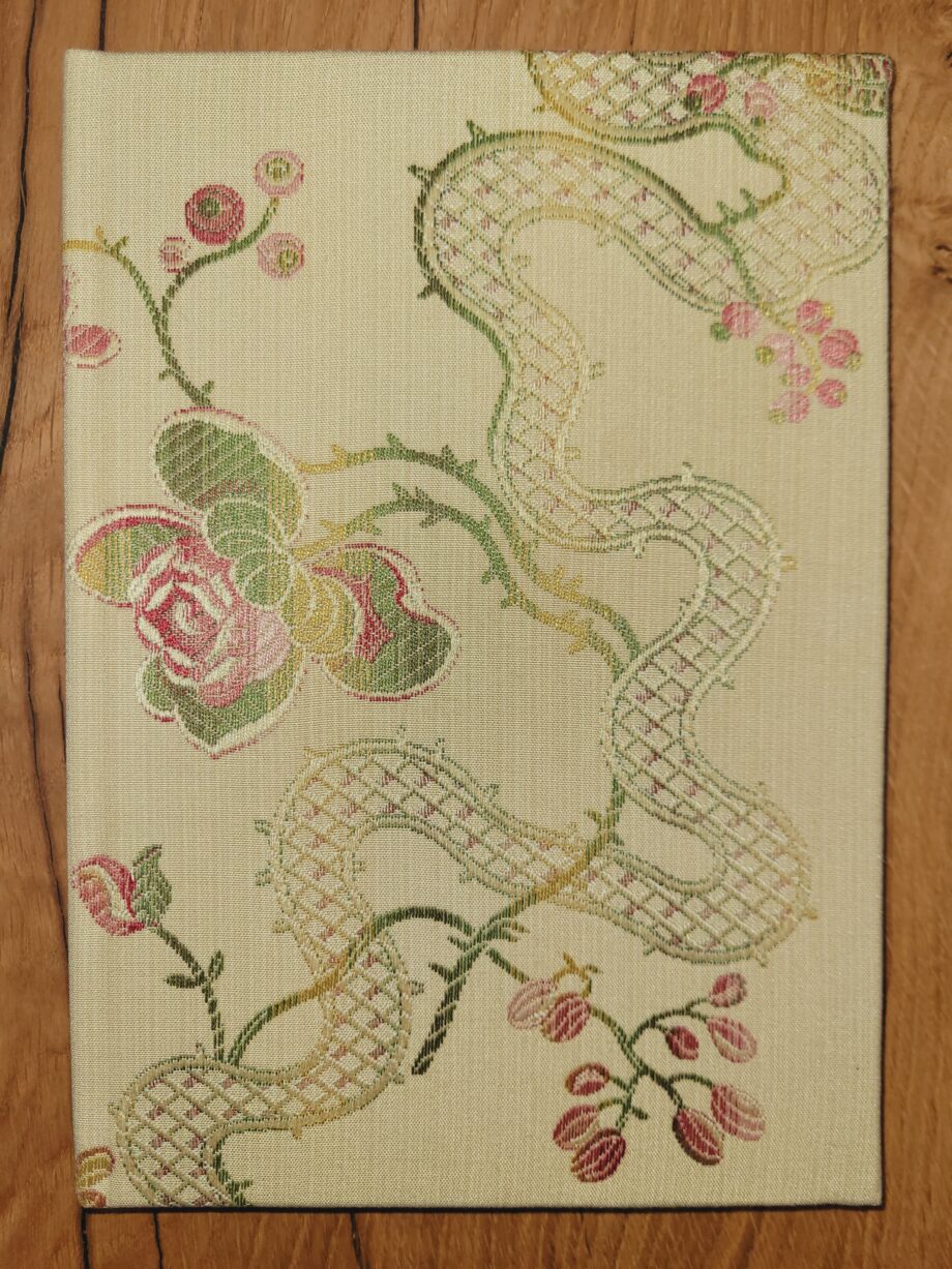 A notebook with an off-white cover adorned with green and pink roses.