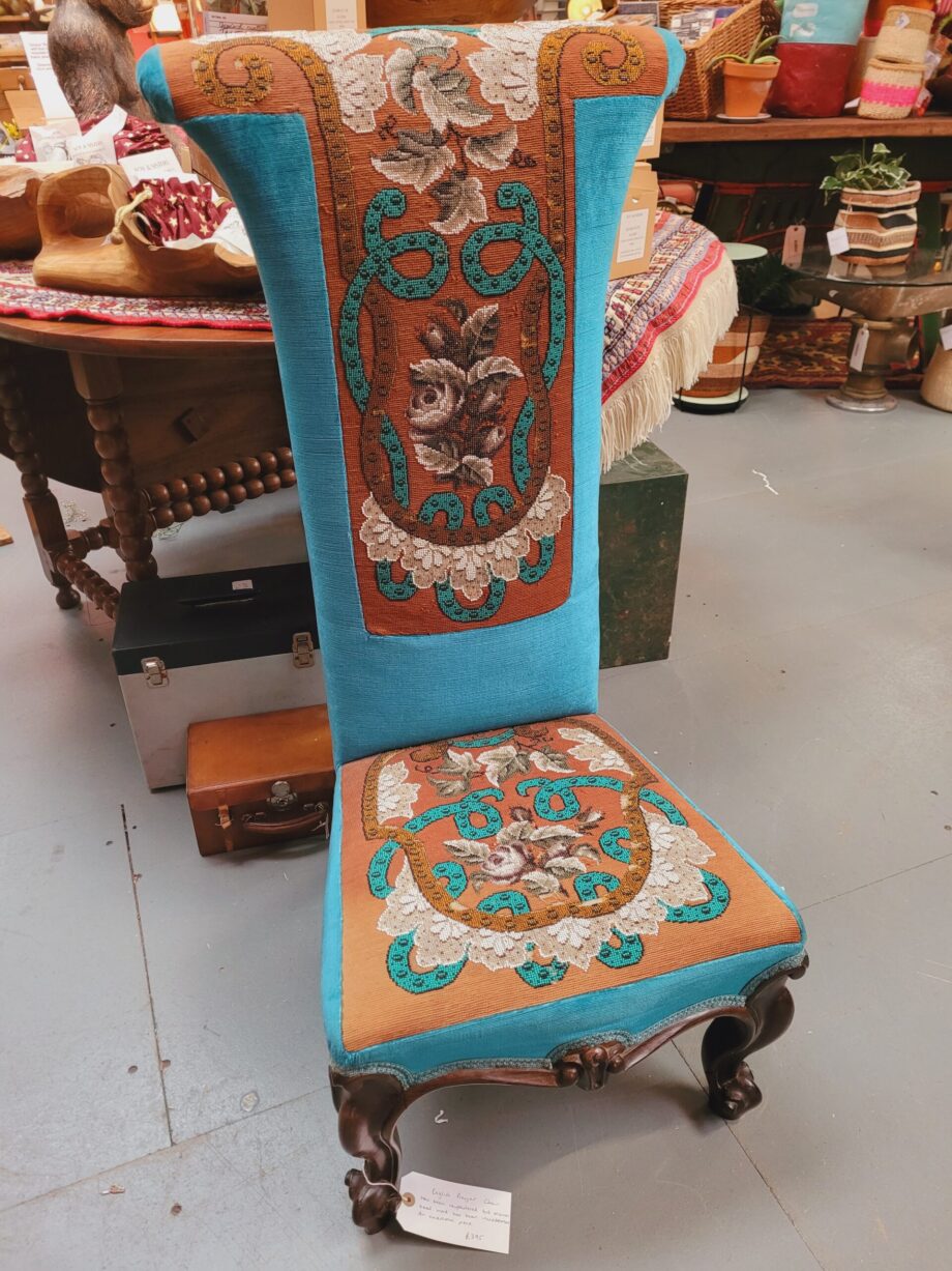 A wooden prayer chair reupholstered with teal and brown floral fabric