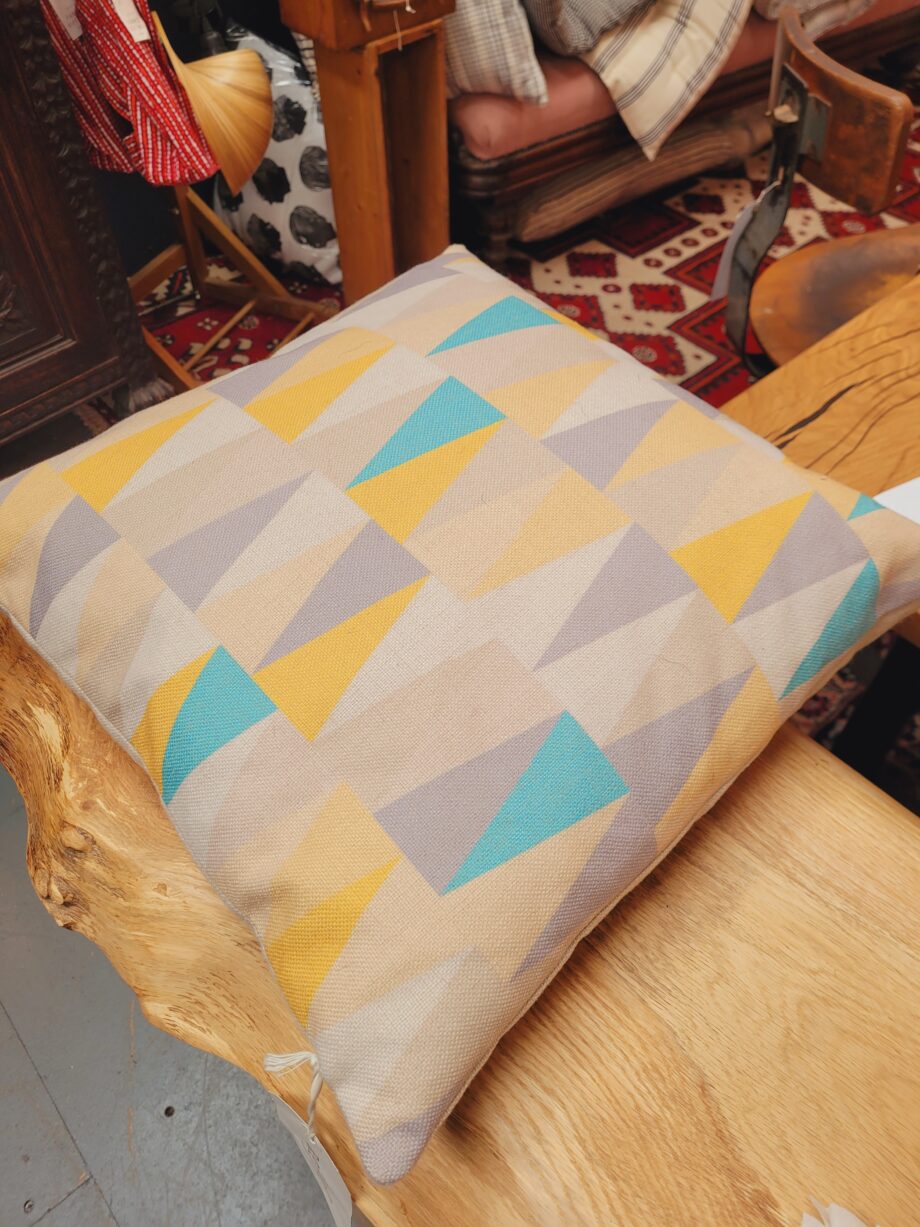 A cushion with a triangle print in pastels.