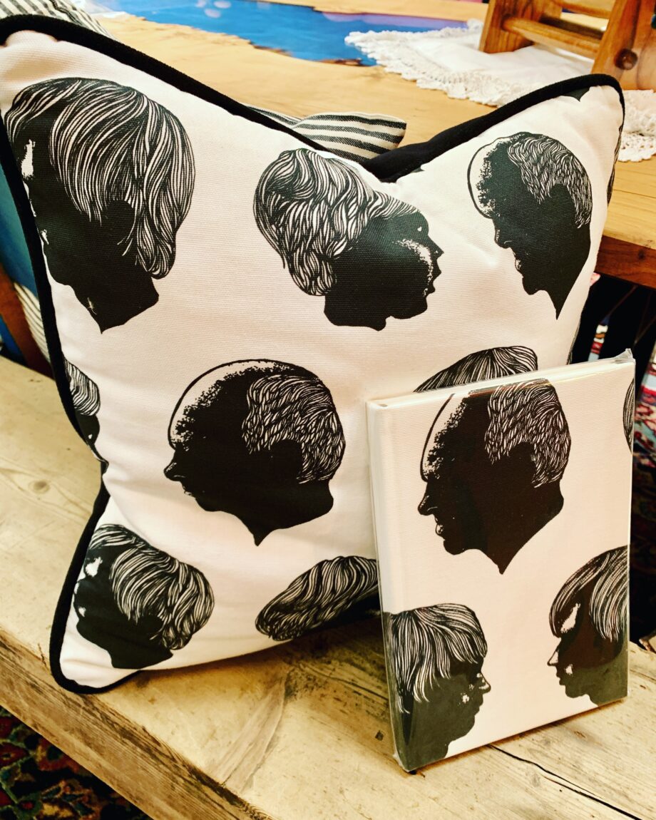 A cushion with a black and white fabric with heads on it.