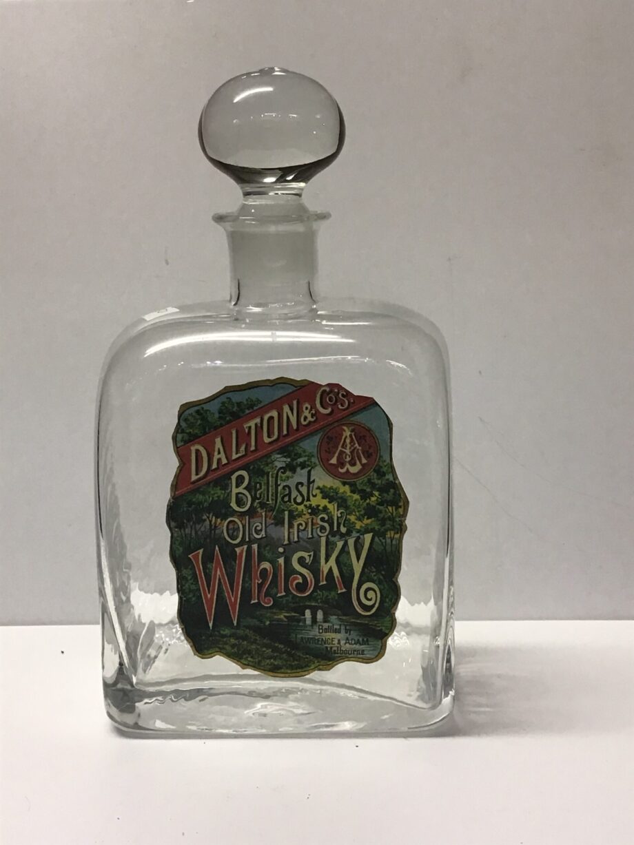 A square bottle with a multicoloured label and a glass topper.