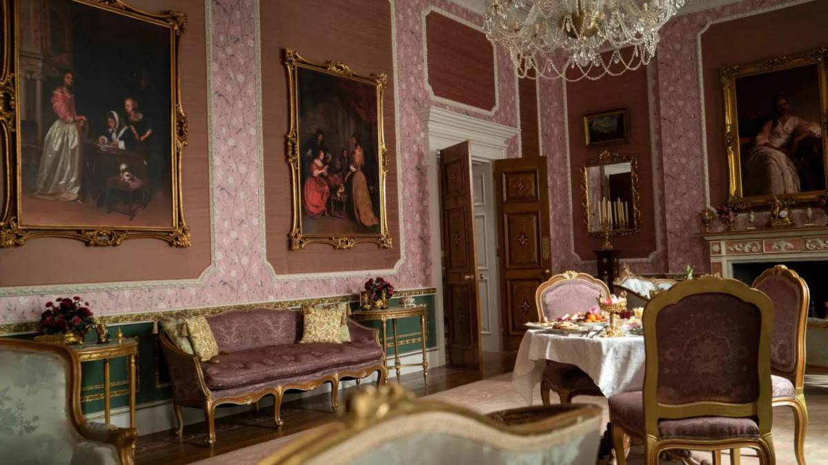 A Regency style living room with pink walls and furniture. 