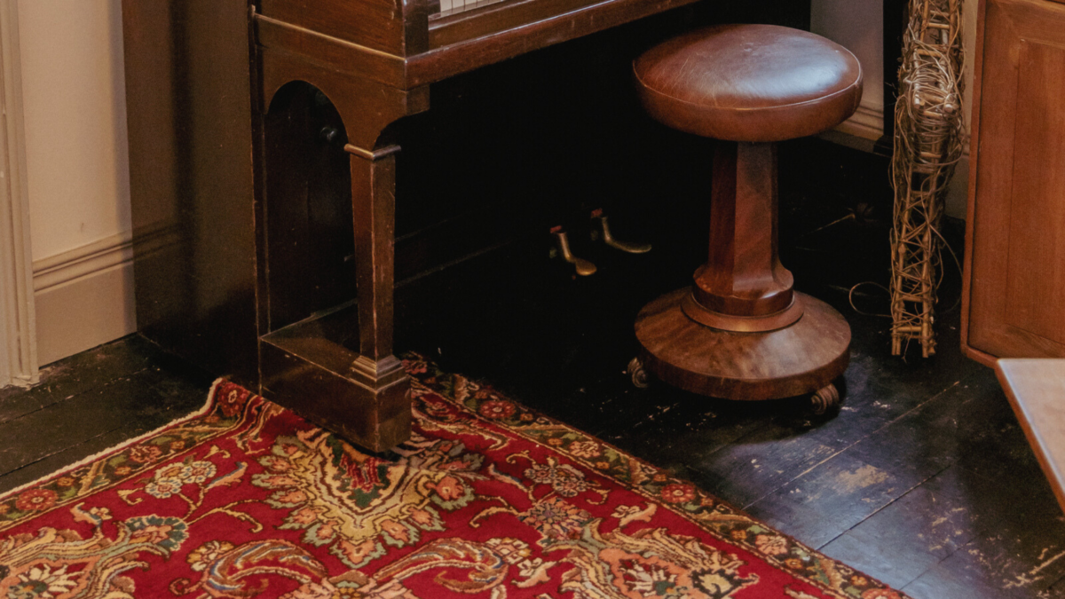 The leg of a piano on top of a Persian rug.