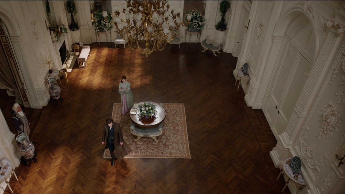 An above shot of a room in Bridgerton with a chandelier at the top.