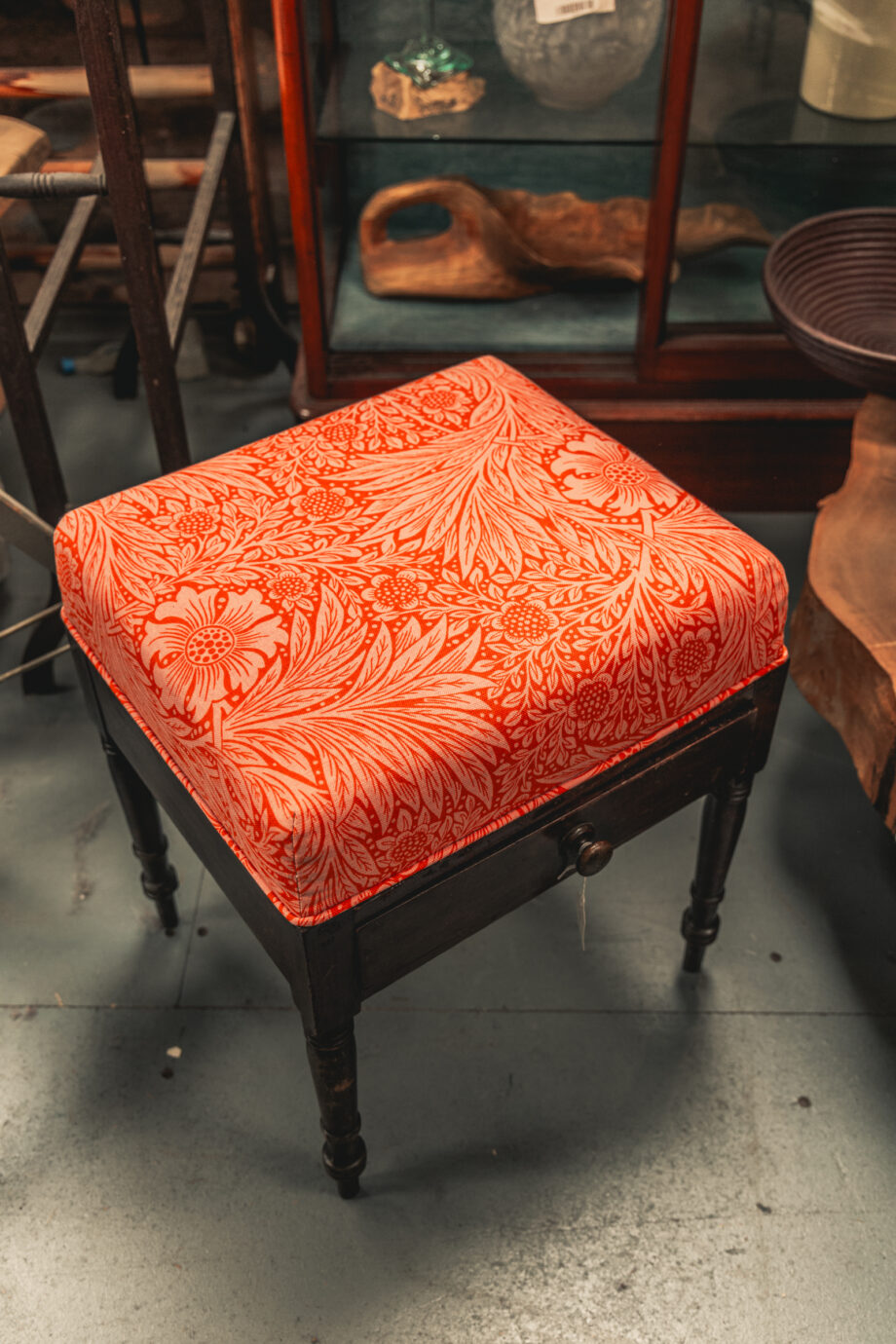 A wooden stool reupholstered with bright orange fabric