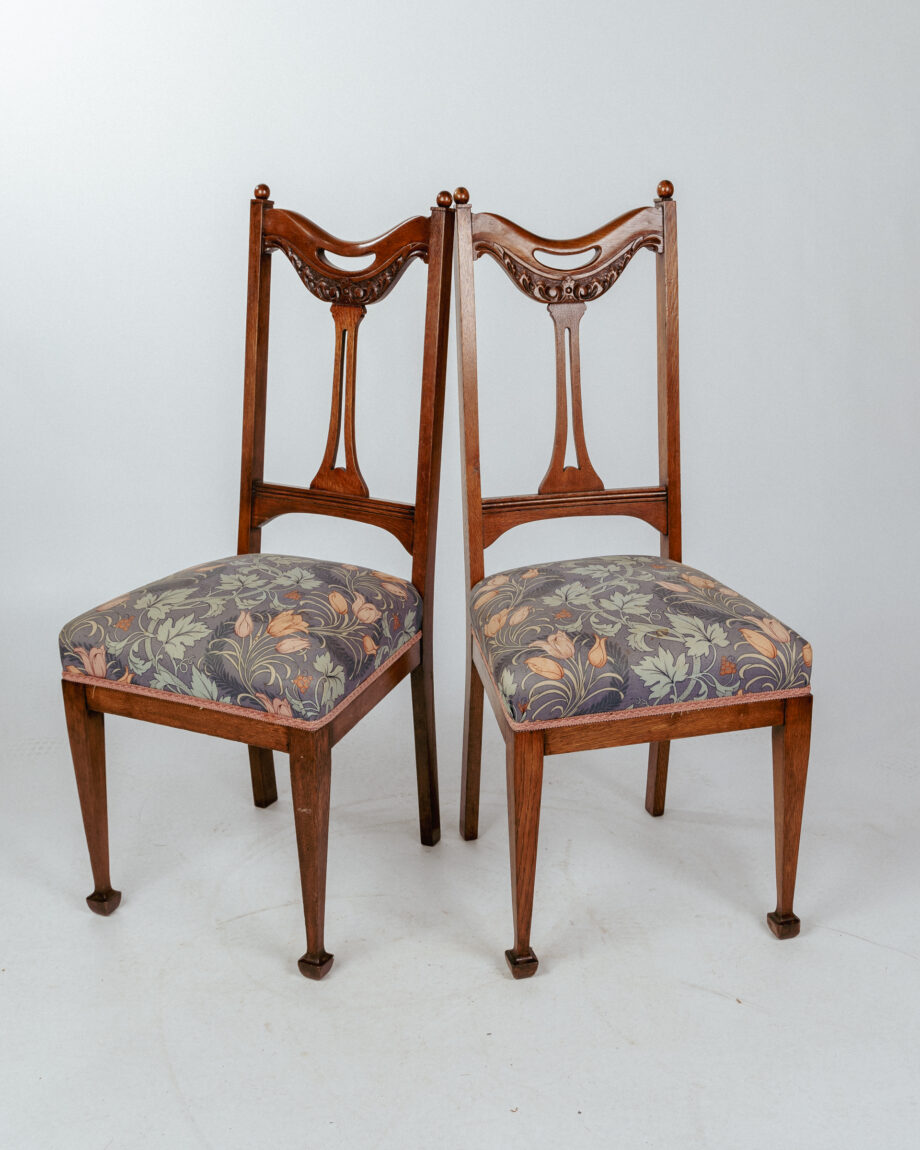 Two wooden dining chairs with floral upholstery on the seats.