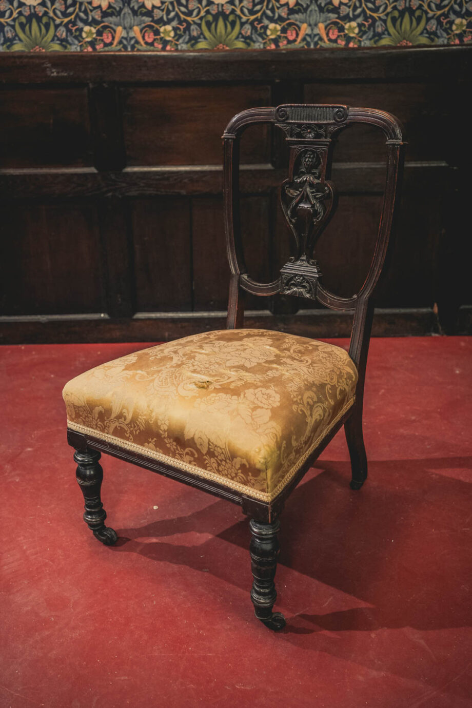 A wooden victorian chair with a gold upholstered seat