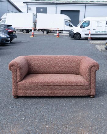 Vintage sofa featuring a red floral pattern fabric, rounded arms, and dark wood feet.